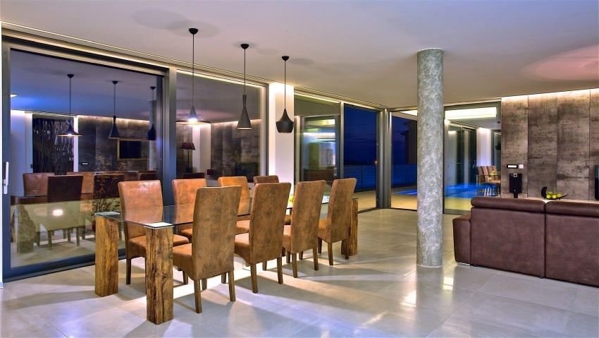 Table à manger avec chaises en cuir et vue sur la piscine éclairée