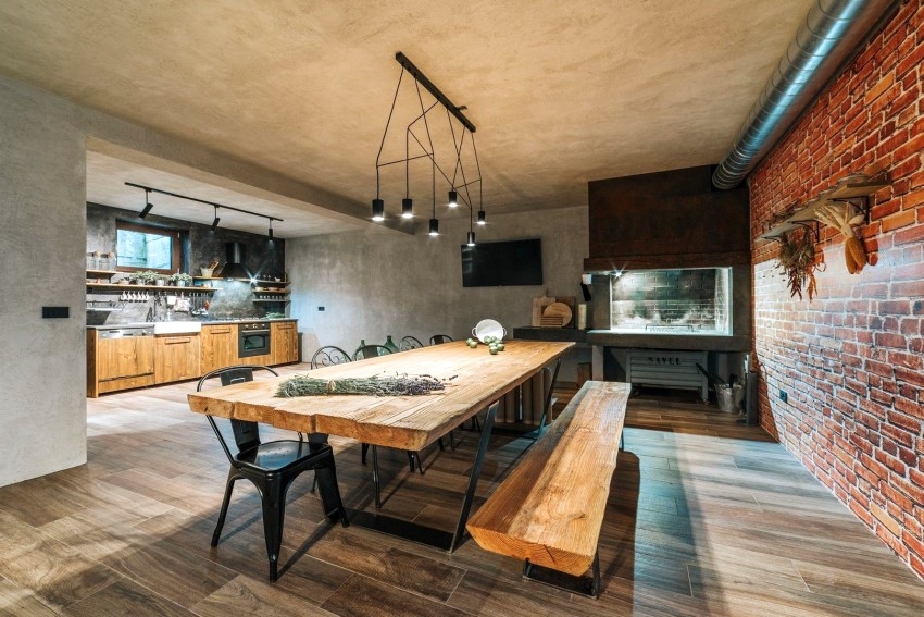 Table à manger en bois massif devant un mur en briques et une cuisine ouverte