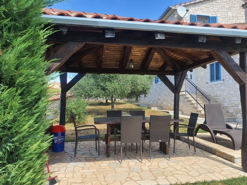 Pavillon couvert avec table à manger à côté de la maison en pierre