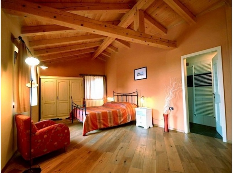 Chambre avec poutres en bois, lit en fer et accès à la salle de bains
