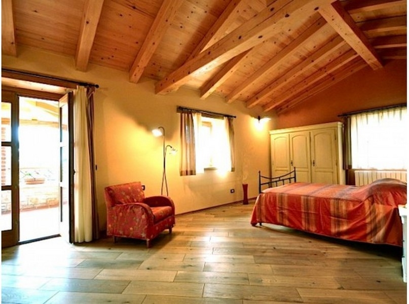 Chambre avec plafond à poutres en bois et fauteuil rouge