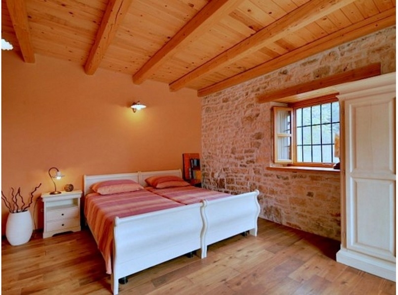 Chambre avec deux lits blancs et mur en pierre naturelle
