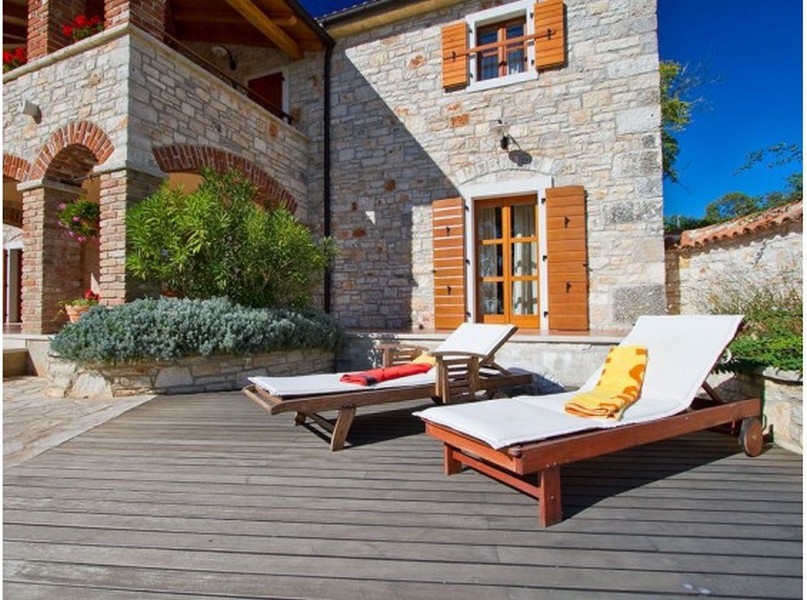 Terrasse en bois avec transats devant la façade en pierre naturelle