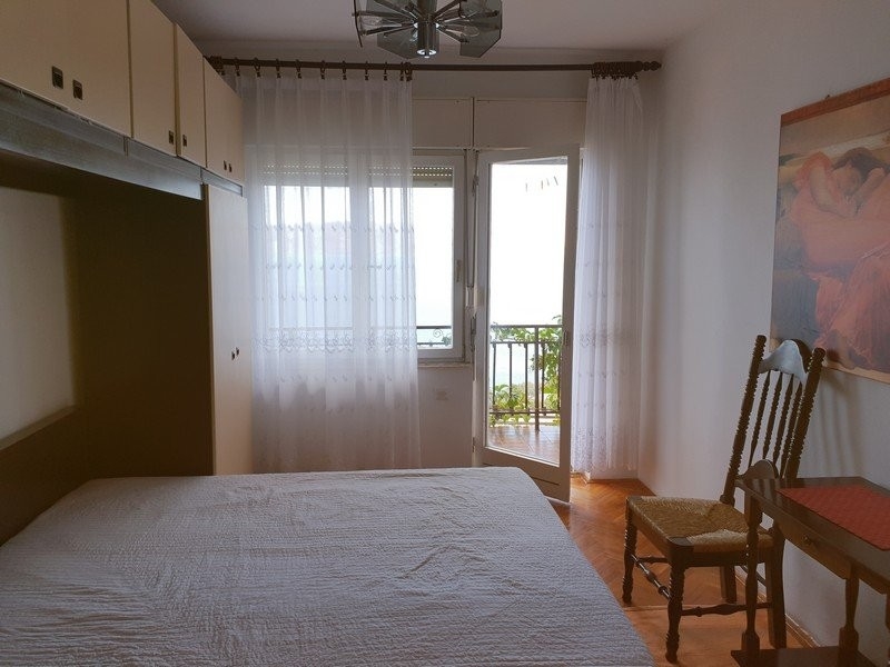 Chambre avec placard en surplomb et porte-fenêtre de balcon avec rideaux