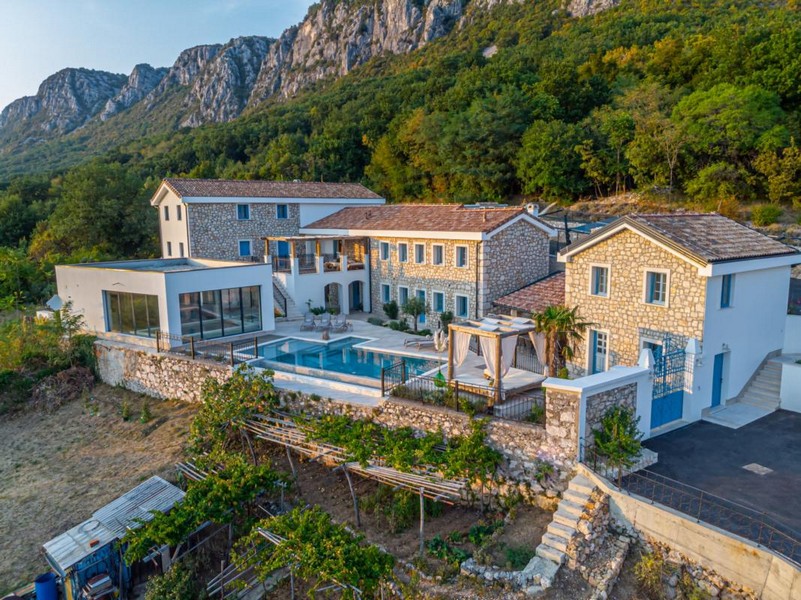 Domaine de maisons en pierre avec piscine devant la paroi montagneuse