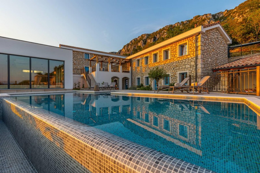 Piscine devant les maisons en pierre dans la lumière du soir sous la paroi rocheuse