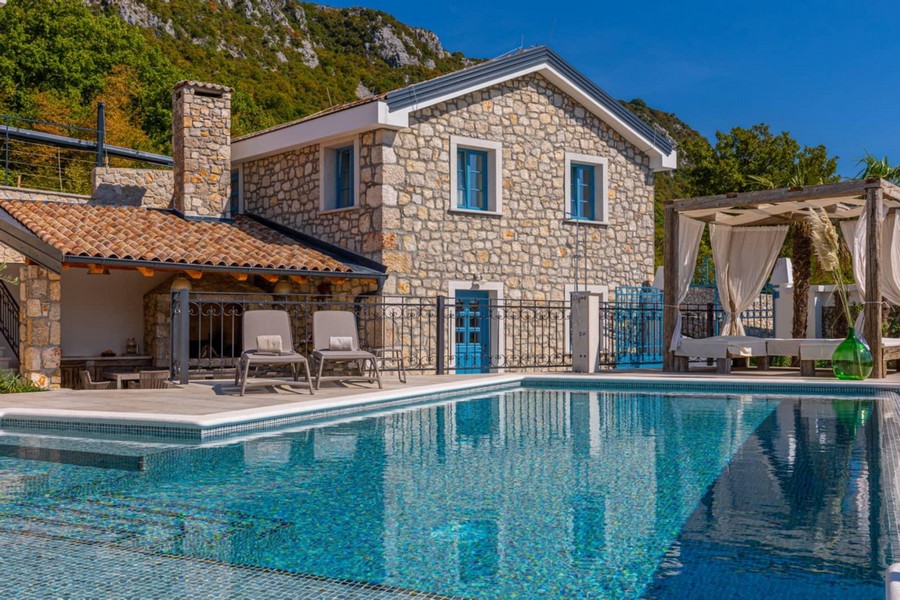 Maison en pierre avec volets bleus au bord de la piscine