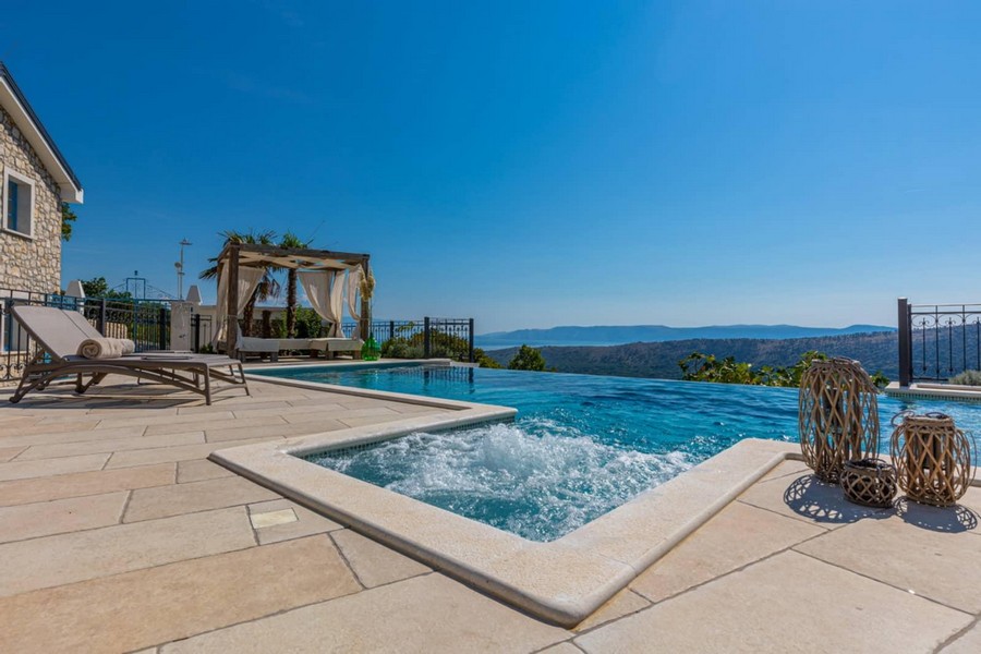 Jacuzzi à côté de la piscine à débordement avec pavillon et vue dégagée