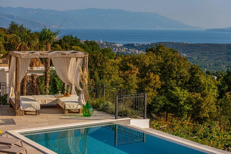 Lounge avec rideaux au bord de la piscine au-dessus de la côte