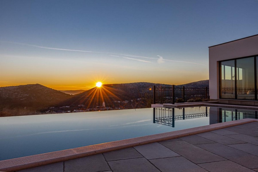 Piscine à débordement au coucher du soleil au-dessus des collines