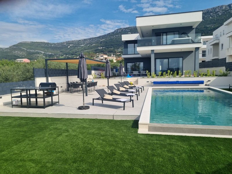 Piscine avec bains de soleil et parasols devant les montagnes