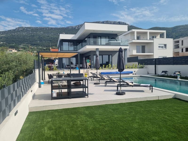 Gazon synthétique et terrasse de la piscine avec pergola devant la crête de la montagne