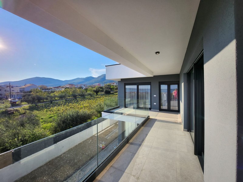 Loggia avec garde-corps en verre et vue sur les prés jusqu'aux montagnes