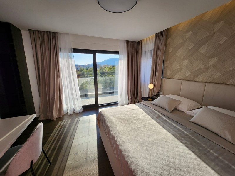 Chambre beige avec lit double et fenêtre donnant sur la terrasse