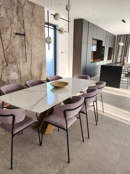 Table à manger en marbre avec huit chaises devant le mur en pierre