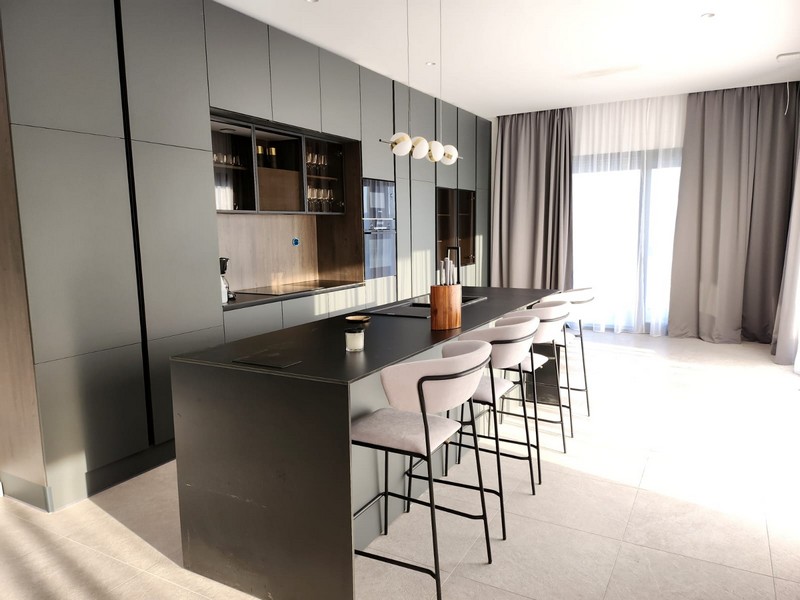 Cuisine sombre avec long îlot de cuisson et tabourets de bar