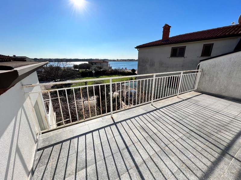 Terrasse ensoleillée avec garde-corps blanc et vue sur la lagune