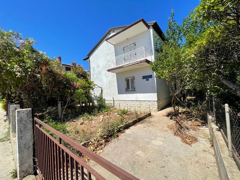 Maison avec balcon derrière le portail métallique à l'entrée