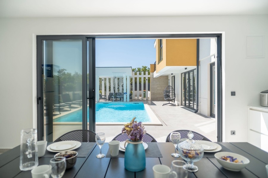 Table dressée avec vue à travers la porte vitrée coulissante sur la piscine