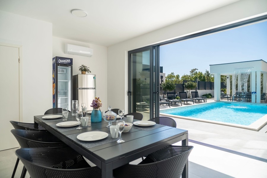 Coin repas avec grande porte vitrée coulissante donnant sur la terrasse de la piscine