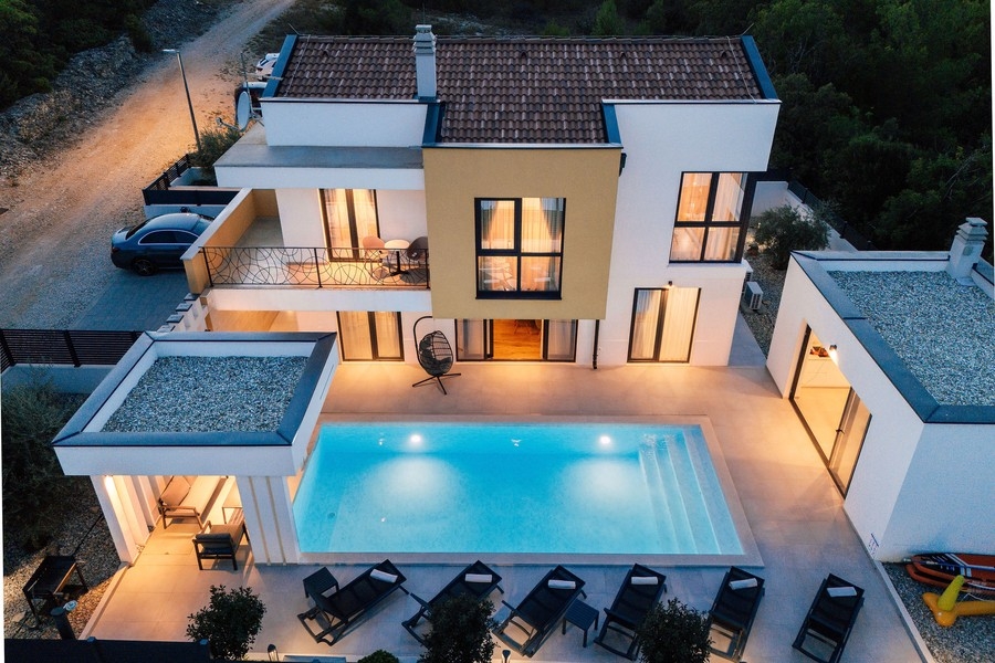 Vue aérienne de la villa avec piscine et bains de soleil le soir