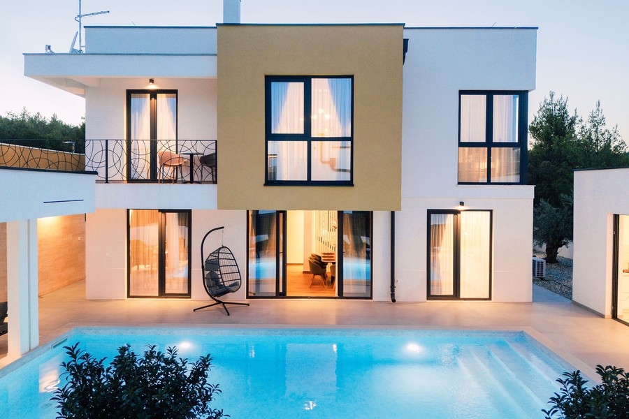 Façade de la maison avec piscine éclairée et fauteuil suspendu
