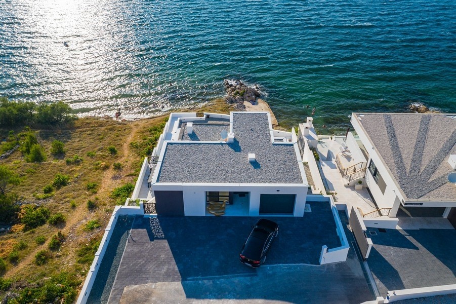 Maison à toit plat avec cour devant, directement sur la côte rocheuse, vue d'en haut