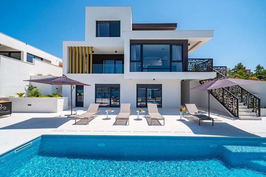 Villa avec transats au bord de la piscine et ornements métalliques à l'escalier