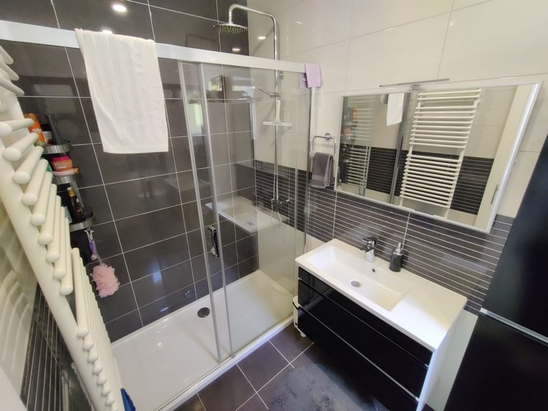 Salle de bains avec carrelage brun et douche.