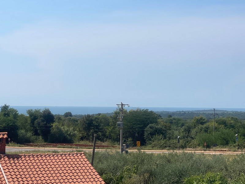 Toit de tuiles au premier plan et mince bande de mer à l'horizon
