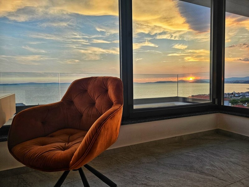 Fauteuil à la fenêtre d'angle devant le coucher de soleil sur la mer