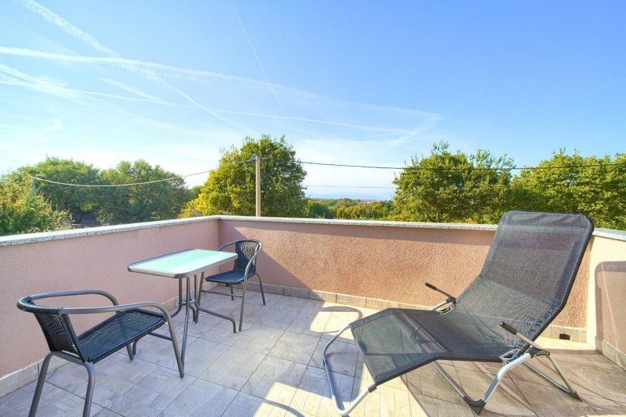 Terrasse avec vue sur l'environnement verdoyant et sur la mer.