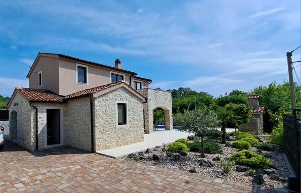 Maison à façade en pierre naturelle et massif de gravier avec olivier