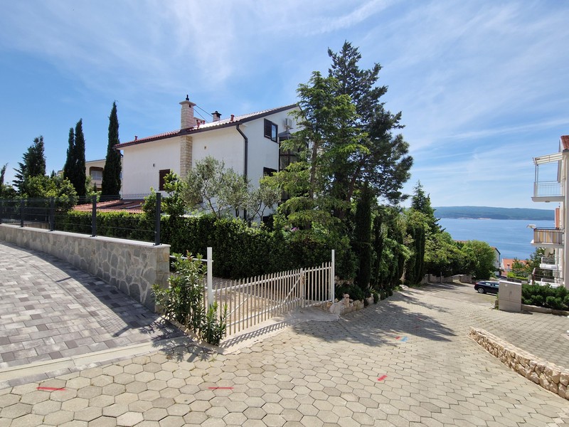 Vue extérieure de la maison avec allée d'accès et vue sur la mer