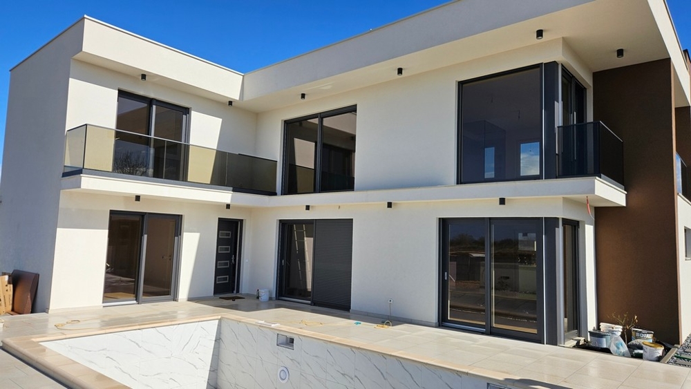 Maison blanche avec balcons en verre et piscine en gros œuvre