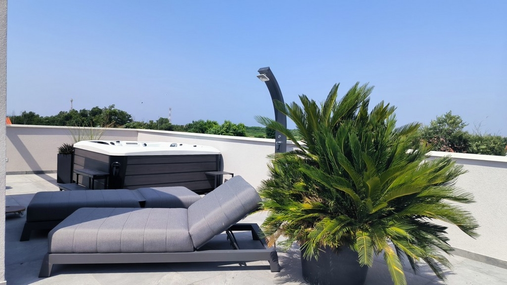 Toit-terrasse avec transat, jacuzzi et vue sur la verdure.
