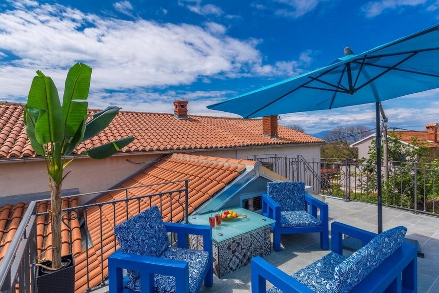 Toit-terrasse avec meubles bleus et parasol au-dessus des tuiles