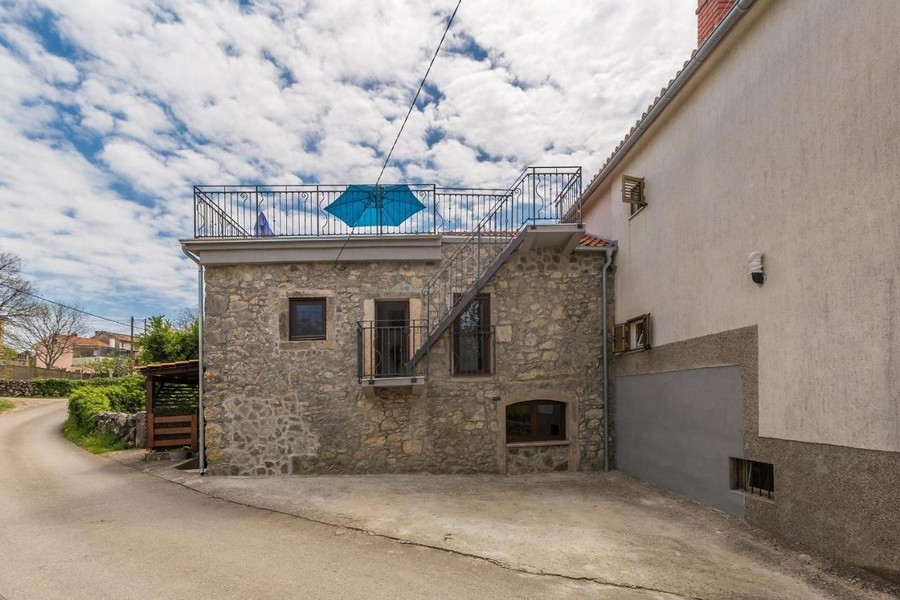 Maison en pierre avec escalier extérieur menant au toit-terrasse dans la ruelle