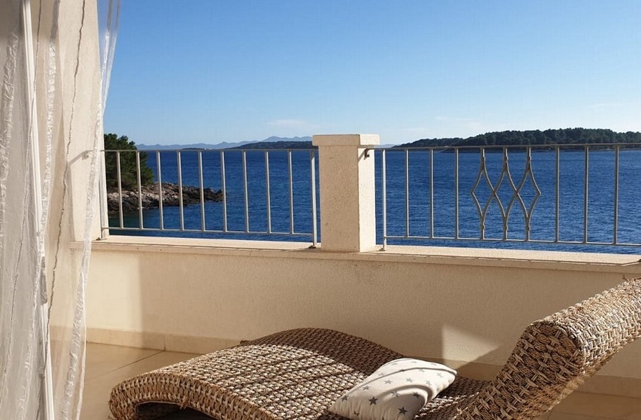 Terrasse avec vue mer et fauteuil relax en rotin.