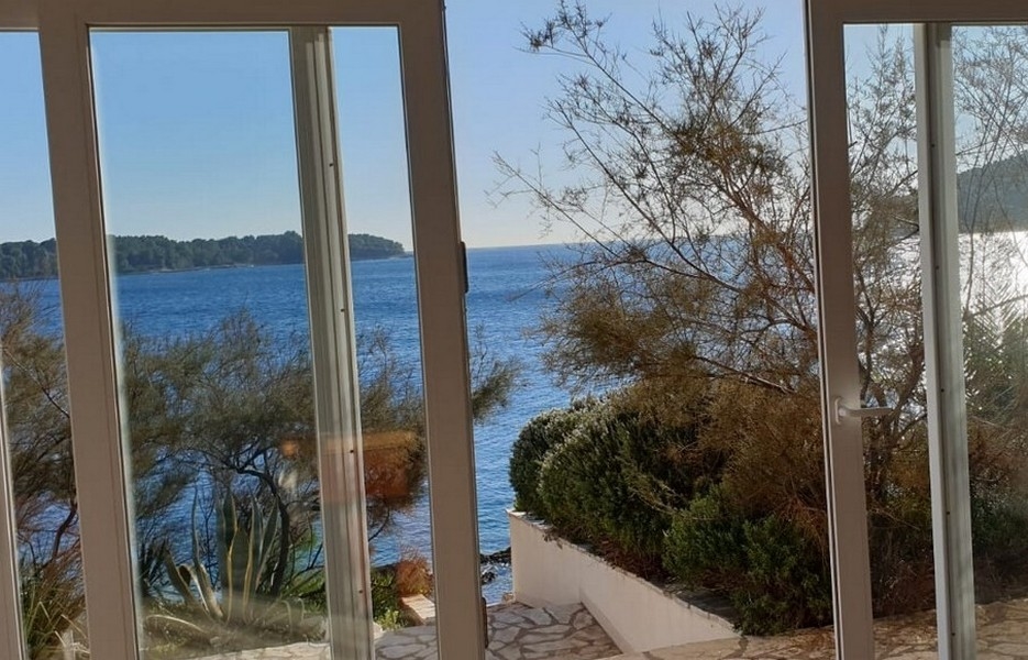 Vue mer depuis le séjour à travers les grandes baies vitrées du rez-de-chaussée de la villa.