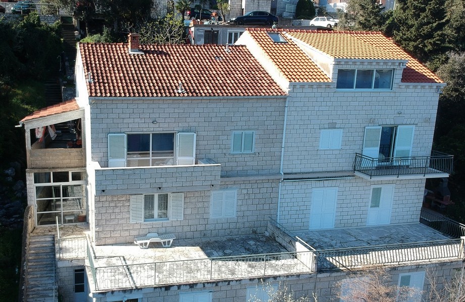 Maison en pierre avec volets bleu clair et toit de tuiles vue d'en haut