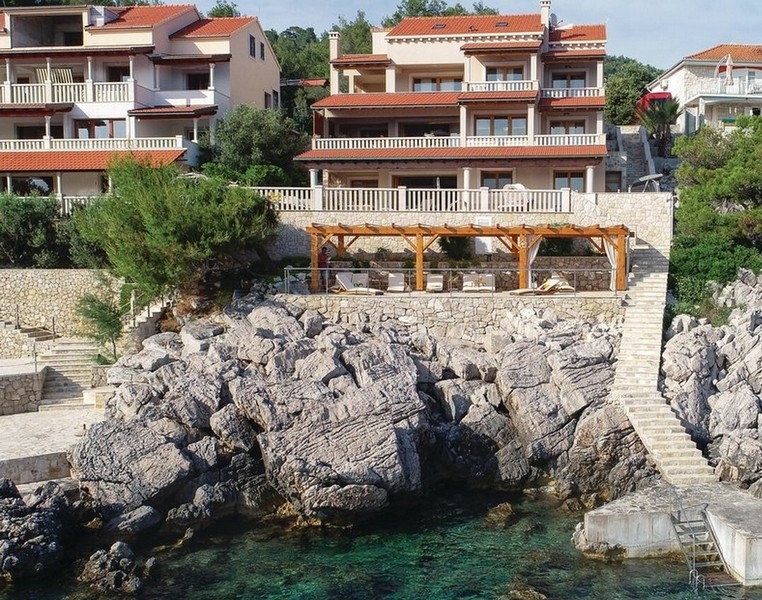 Maisons au-dessus des rochers avec pergola en bois et escalier de baignade