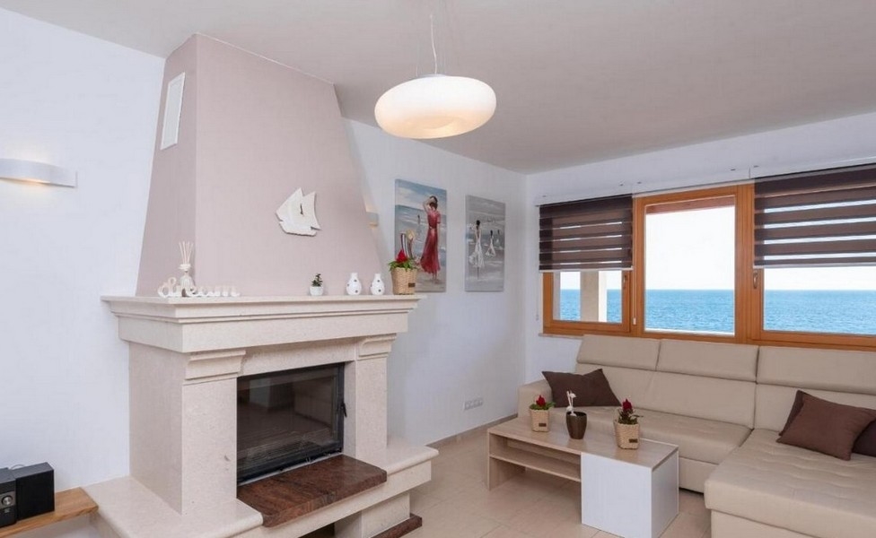 Cheminée dans le salon avec vue mer et un canapé clair.