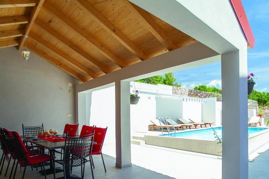 Coin repas couvert et vue sur la piscine.