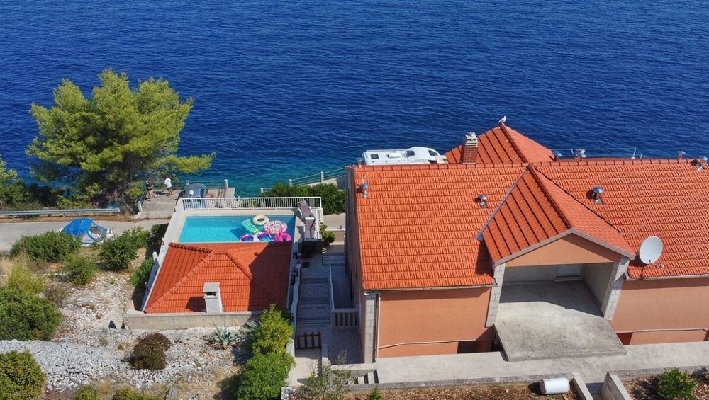 Maison avec piscine sur la côte rocheuse au-dessus de l'eau d'un bleu profond