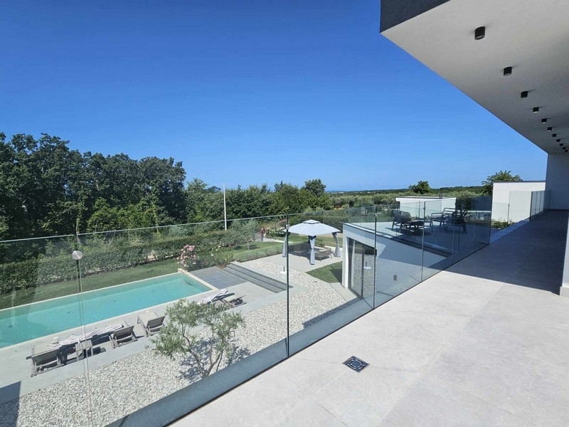 Vue de la loggia par-dessus la piscine et le jardin sur la verdure