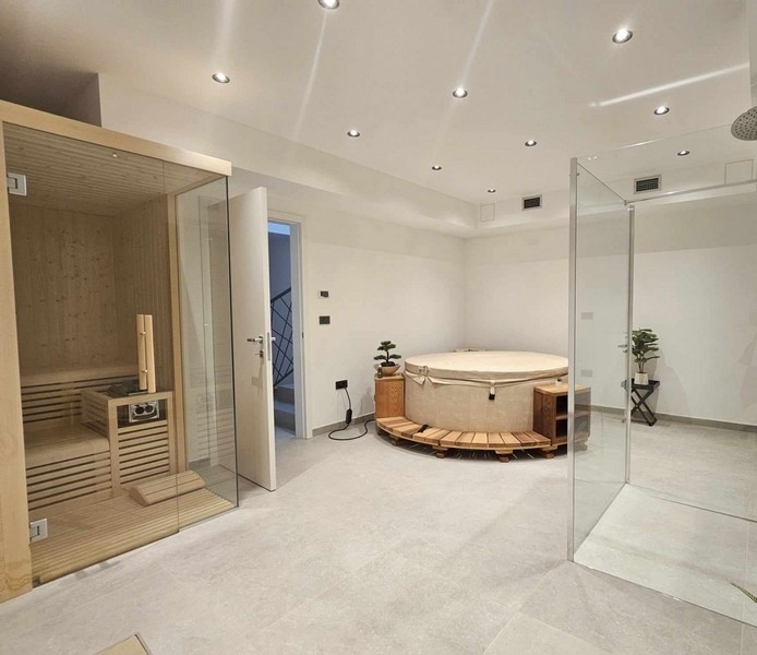Grand espace bien-être avec jacuzzi, sauna et douche.