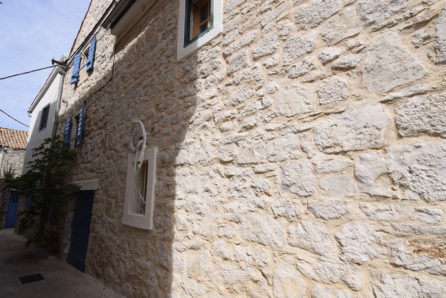 Façade en pierre naturelle avec volets bleus dans la ruelle étroite