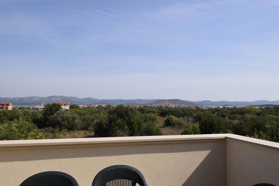 Vue depuis le toit-terrasse sur les oliveraies jusqu'au village au bord de l'eau