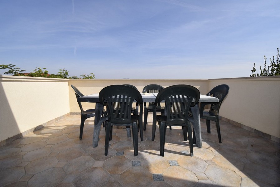 Spacieuse terrasse ouverte avec simples chaises de jardin.